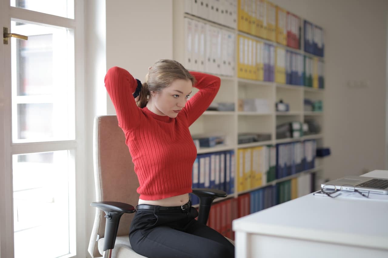Young lady in red top stretching at desk