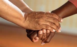 Image of two people holding hands. Make a positive change for others!